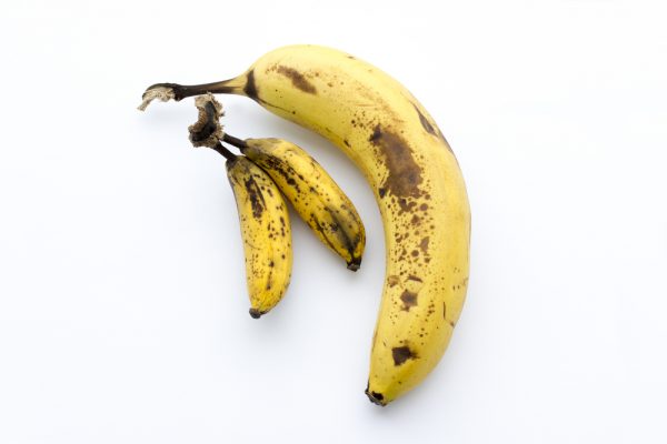 shutterstock_400025101 Two baby bananas lay next to one large banana on white background by shutterstock.com